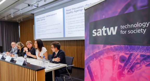 SATW banner next to a panel discussion in the conference room.