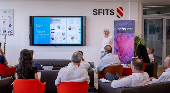 A presentation in a modern conference room with participants and a speaker